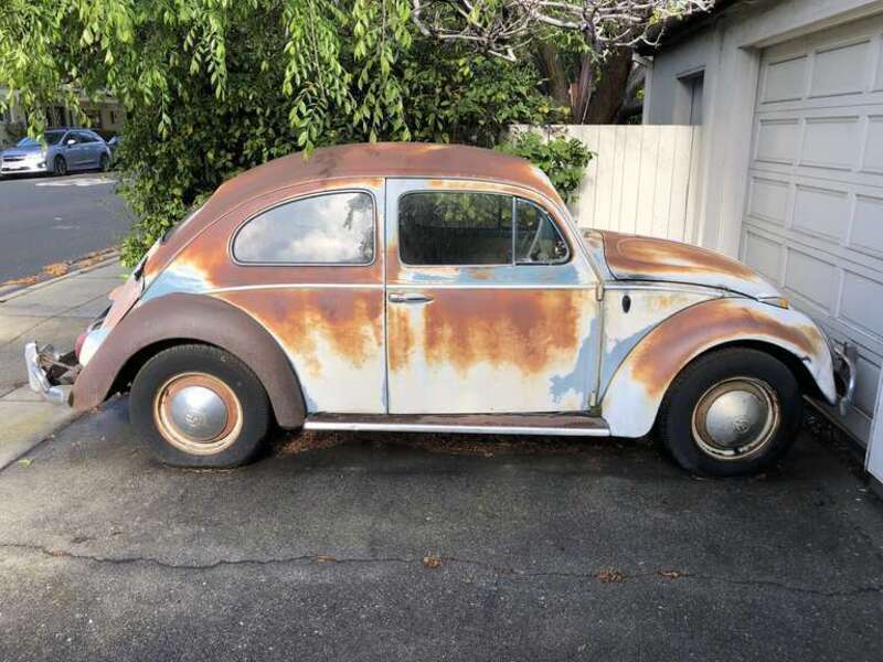 An old and rusted Volkswagen Beetle with a flat tire in a driveway along West Olive Avenue in Sunnyvale, Santa Clara County, California