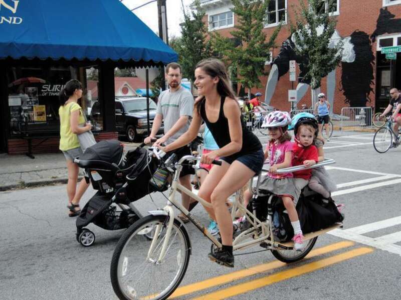 A woman on a cargo bike with three kids ! Two young girls and another child.