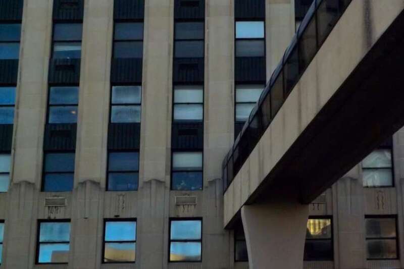 As seen on a January 2023 afternoon from an automobile stopped at the red light at the corner of South Salina and Onondaga Streets in downtown Syracuse, New York: a skybridge (right foreground) carries pedestrians from the Hotel Syracuse parking ramp