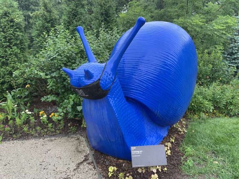 Large snail created by Cracking Art and displayed at the garden at Newfields in Indianpolis Indiana. The snail has a mask on in reference to the COVID-19 pandemic, which had started several month before this photo was taken in June 2020.
