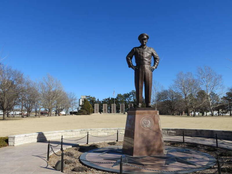 Dwight D. Eisenhower statue in &quot;Champion of Peace&quot; circle, with memorial pylons in background.