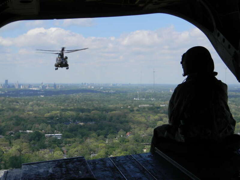 Perched precariously on the ramp of a CH-47 Chinook helicopter above Piedmont Park in downtown Atlanta, a Georgia National Guard crew chief carefully eyes another Guard CH-47 flying in close formation as the two aircraft give Cobb County's Honorary