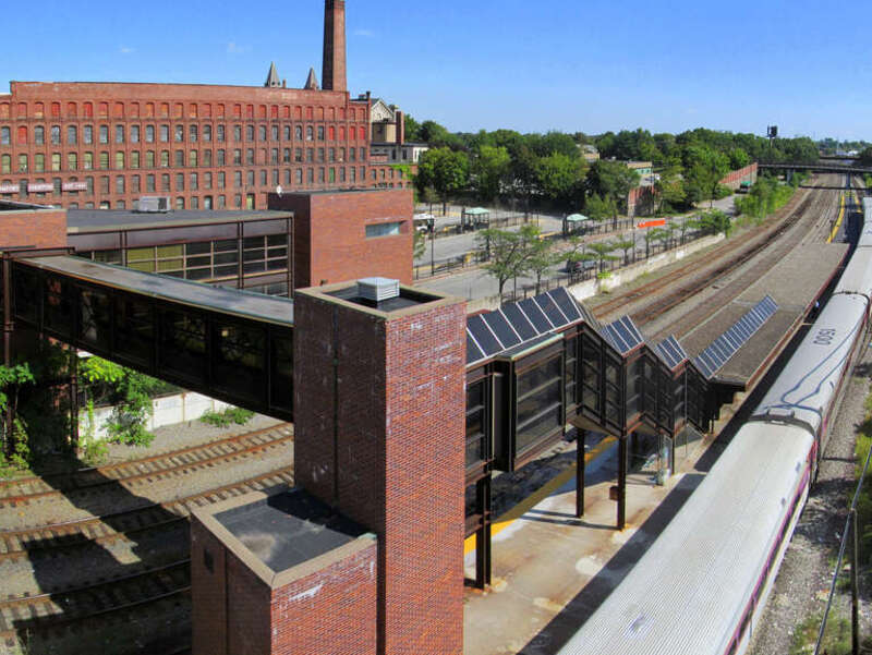 Lowell station viewed from the roof of the west parking garage in August 2012. The commuter rail platform with an MBTA train is at bottom right, the pedestrian overpass at bottom left, the station building at center left, and the bus bays at top