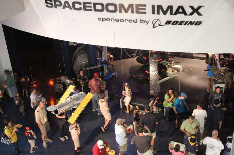 Patrons await entry to the IMAX theater at the United States Space &amp;amp; Rocket Center.  A model of Hubble Space Telescope is suspended in the foreground.