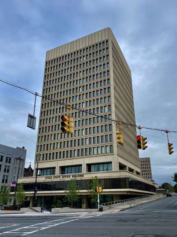 The Utica State Office Building, 207 Genesee Street at Blandina Street, as seen on an August 2021 afternoon. With a simple, angular design of regular rows and columns of narrow windows deeply recessed into a smooth-textured façade of concrete panels,
