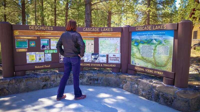 Woman viewing Cascade Lakes Welcome Station Interpretive Sign on the Deschutes National Forest in Central Oregon