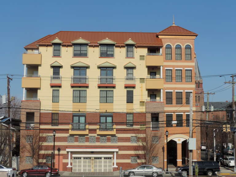 Looking west across Avenue E from 22nd Street station at apartment house on a sunny morning.