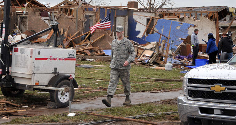 An Air Force member moves through a neighborhood looking for people in need of help in the aftermath of the devastating tornado that ripped through Moore Okla., May 20, 2013. One of the hundreds of Oklahomans to lose their homes is being interviewed