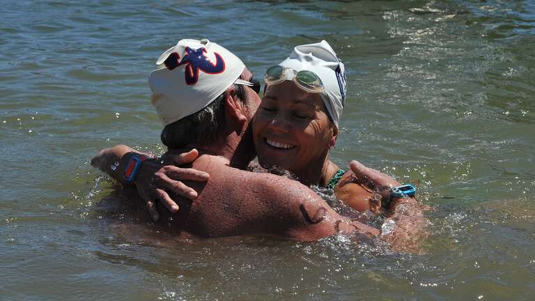 Phil Sidenberg, age 59, from Thousand Oaks, CA, and Deena Exparaza age 51, of Newbury Park, CA, participated in the 2016 SoCal Cup Open Water Festival. Sidenberg is pictured hugging his friend Exparaza after she crosses the finish line. Phil