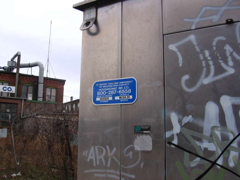 A crossing signal sign at a gate along Canal Street in Shelton, Connecticut, milepost 104.20