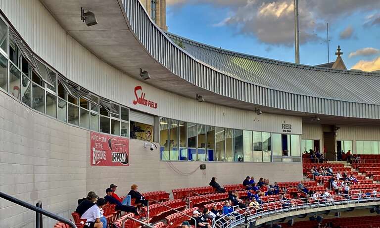 A view of the upper deck and press box at Sahlen Field during a September 2021 game between the Buffalo Bisons and the Syracuse Mets. The &quot;RER&quot; monogram above the press box windows at far right refers to former Bisons team owner Robert E. Rich Sr.,