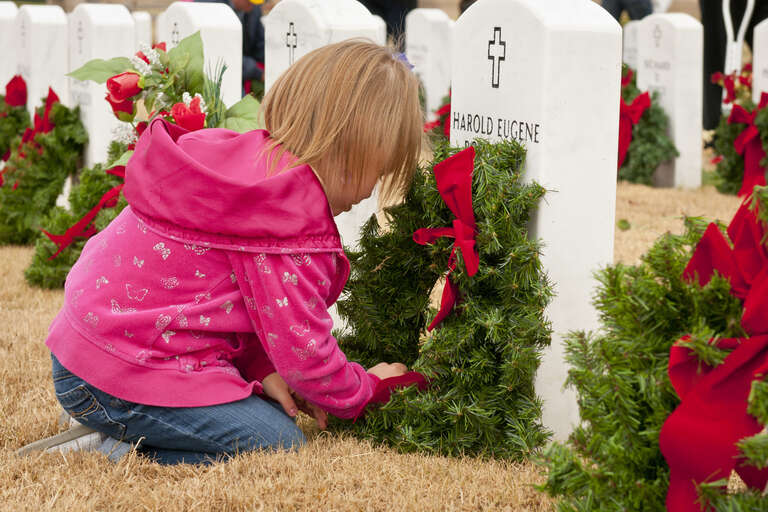 Carley Lawry, 5, places a wreath on a headstone at the Central Texas State Veterans Cemetery Nov. 30, 2013. More than 1,000 volunteers from the Fort Hood/Killeen area joined family members of the fallen to place more than 5,000 wreaths on the grave