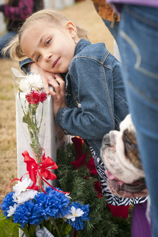Abby Mattox, 6, hugs her grandfather's headstone at the Central Texas State Veterans Cemetery after placing a Christmas wreath on it, Nov. 30, 2013. More than 1,000 volunteers from the Fort Hood/Killeen area joined family members of the fallen to
