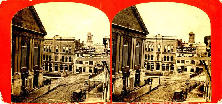 SV-059 — Nelson Dionne Collection. View down Essex Street from a building on that street, looking toward Washington Street (contrary to the printed title), with a particular focus on some of the buildings at Town House Square.
At left stands the