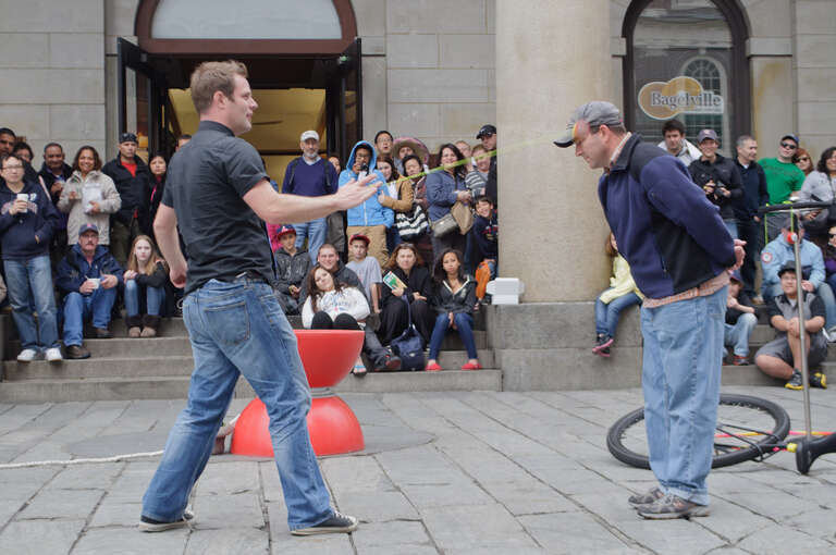 Faneuil Hall and Quincy Market are surrounded by portrait artists and street performers who cater to the shoppers and tourists in the area.

This performer is using his yo-yo to strike a quarter resting on the visitor's earlobe.