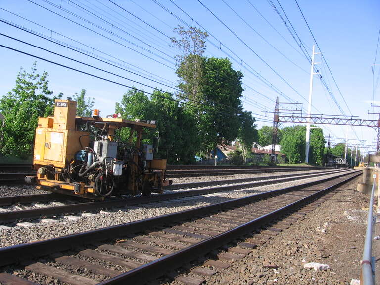 A ballast tamping machine on track 3 at East Norwalk station.  Other maintainence of way equipment is visible further down the line looking east.