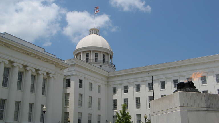 The Alabama State Capitol next to the eternal flame of the Alabama Veterans Memorial.