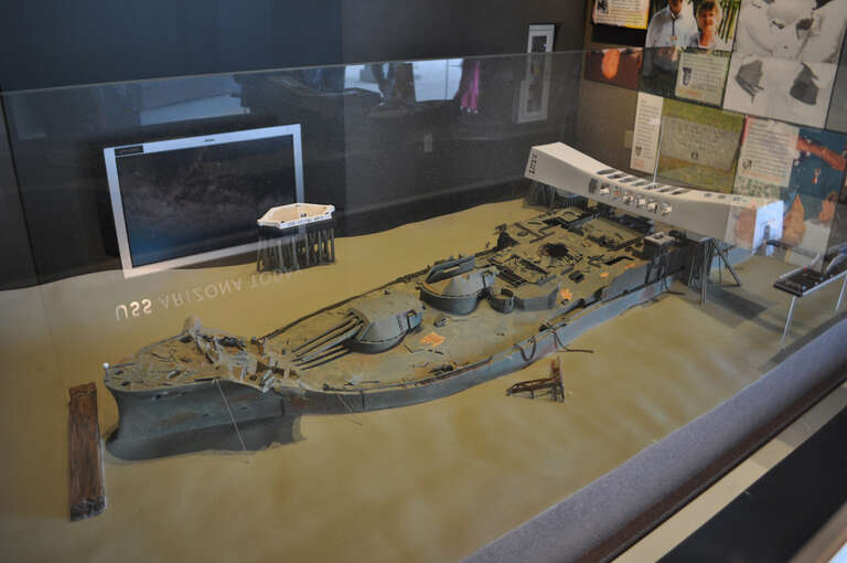 This model shows what the wreckage of the Arizona looks like today, with the memorial on top.
After being sunk by a massive Japanese attack in 1941, the ship has remained where it was sunk. Above-water structures were removed in 1961, to make way for