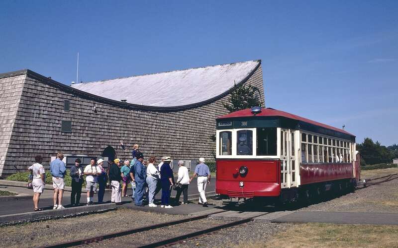 Astoria Riverfront Trolley car 300 stopped next to the Columbia River Maritime Museum (in Astoria, Oregon), with people waiting to board. The photo was taken in July 1999, only the second month of operation of the trolley line.  The Maritime Museum