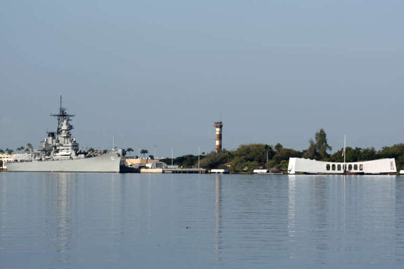 The USS Missouri moored near the USS Arizona Memorial at Pearl Harbor.  The control tower for the former Ford Island Naval Air Station is also shown in the center of the photo.