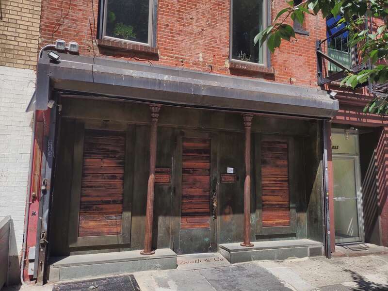 Looking northeast from curbstone at closed Death and Company (cocktail bar) on a sunny afternoon