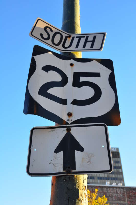 US 25 sign (that has seen better days) affixed on a lamp post along Broadway Avenue, in downtown Asheville.