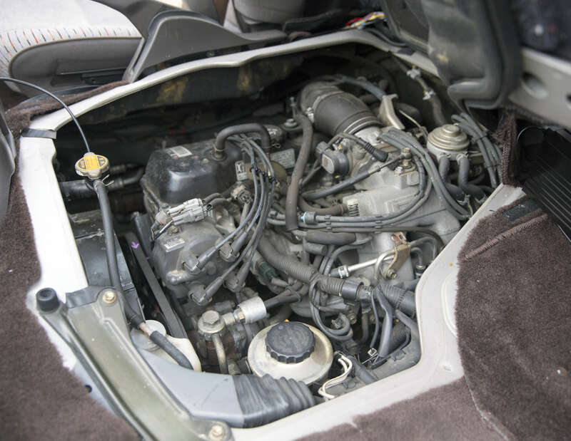 The fuel injected 2.4-liter 2RZ-E engine in a 1994 Toyota HiAce Wagon Super Custom (RZH101G). Well, what can be seen of it underneath the front seats.