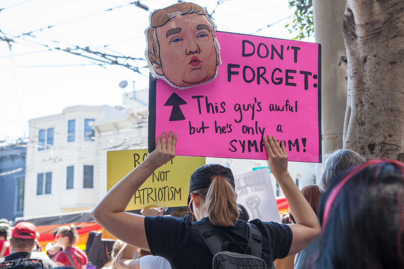 A protester holds a sign with a drawing a Donald Trump and the words &quot;Don't Forget: This guy's awful but he's only a symptom!&quot; at a Patriot Prayer counter-protest in San Francisco.