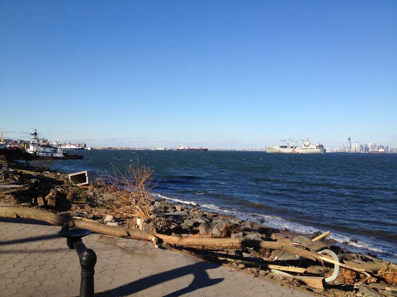 The Aviation Logistics Support Ship SS Wright (T-AVB 3) enters inner New York Harbor on 5 November 2012 as part of the Hurricane Sandy recovery effort.  In the foreground is debris from the ocean surge of the hurricane left on the walkway between