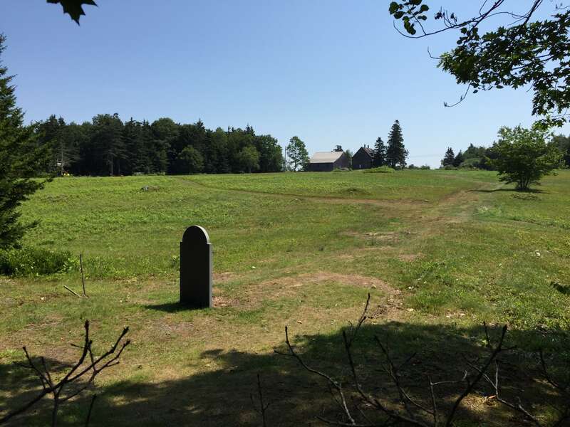 The grave of Andrew Wyeth, with the Olson House on the hill in the background