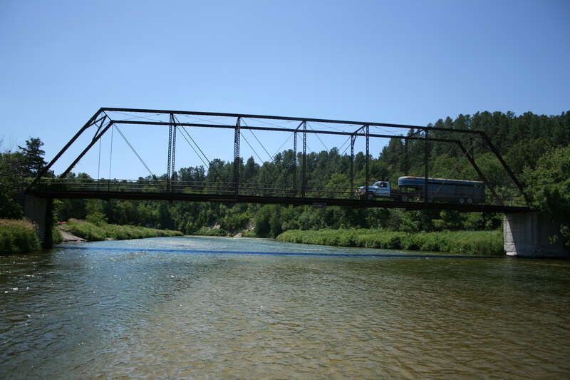 North (upstream) side of Brewer Bridge. Taken from a sandbar in the middle of the Niobrara River.  A blue pickup truck tows a livestock trailer across the bridge.