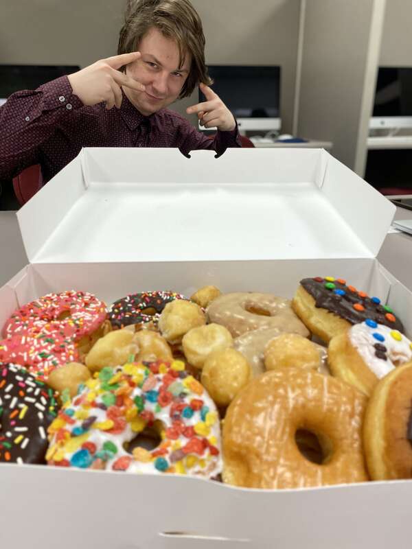 Photo showing American graduate student researcher posing with gourmet donuts.