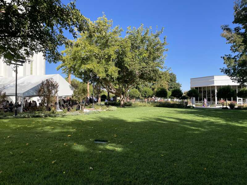 A field of grass is shown in the foreground, on the left is the southeast corner of the St. George Temple, on the right is the visitors center.
