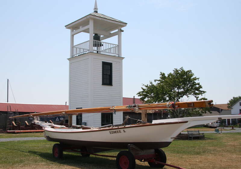Chesapeake Bay log canoe Edmee S. with the Point Lookout Tower in the background at the Chesapeake Bay Maritime Museum, Saint Michaels, Maryland