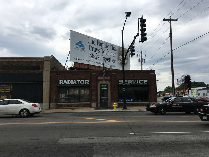A huge billboard looms over a Radiator Service building in downtown Green Bay, WI.