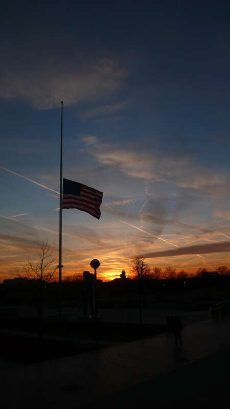 US flag flying at half-staff at sunset in White River State Park, Indianapolis, Indiana, United States.