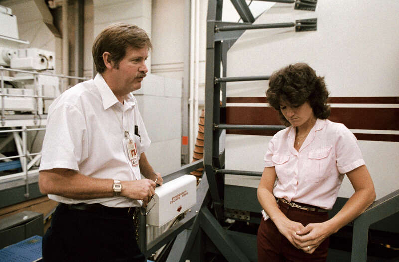 S83-32890 (23 May 1983) --- Astronaut Sally K. Ride, STS-7 mission specialist, stands near the Shuttle Mission Simulator (SMS) in Johnson Space Center's (JSC) Mission Simulation and Training Facility with suit specialist Alan M. Rochford after