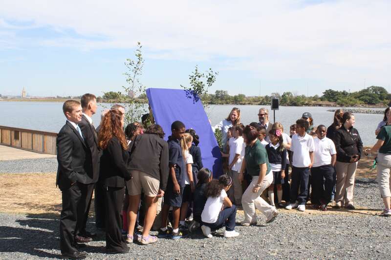 Students from Curtis Bay Elementary School prepare to unveil e Masonville Cove Urban Wildlife Refuge Partnership sign along with partners.