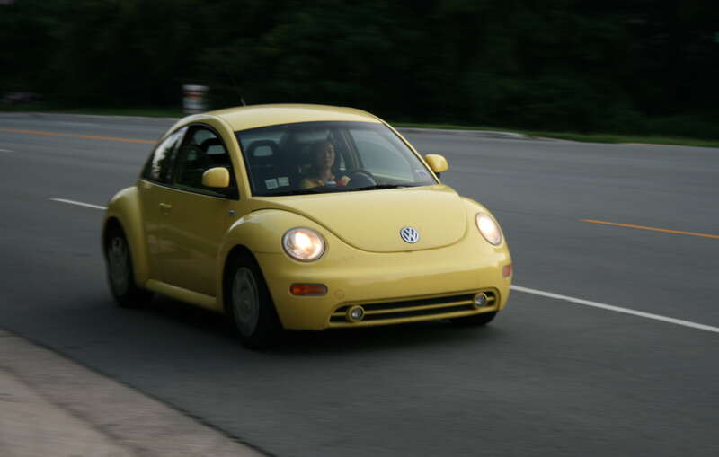 A yellow Volkswagen New Beetle on Franklin St in Chapel Hill, North Carolina in the evening.