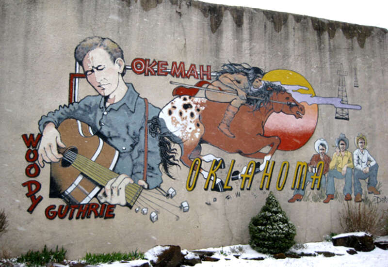 Mural at 510 West Broadway, Hwy. 56, downtown Okemah, Oklahoma, depicting Woody Guthrie and Okfuskee County history. Painted by DeAnna Mauldin in 1994.