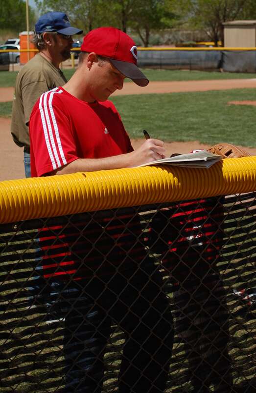 A tee ball coach setting the lineup and fielding positions before the start of a game.  He should do this before the game when all the young tee ball players aren't shouting and begging to be catcher or pitcher or first base.  Photo taken by Vinnie