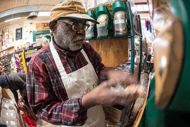 Glut volunteer Tony Green, works quickly to package, weigh, label and deliver cashews to a waiting customer at this worker-owner cooperative store, that serves the Mount Rainier, Maryland community, on Tuesday, March 3, 2015. Mr. Green is retired and