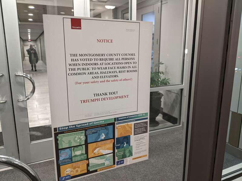 Sign on the door that says &quot;Notice: The Montgomery County Counsel Has Voted to Require All Persons When Indoors At Locations Open To The Public To Wear Face Masks In All Common Areas, Hallways, Rest Rooms And Elevators. (For your safety and the