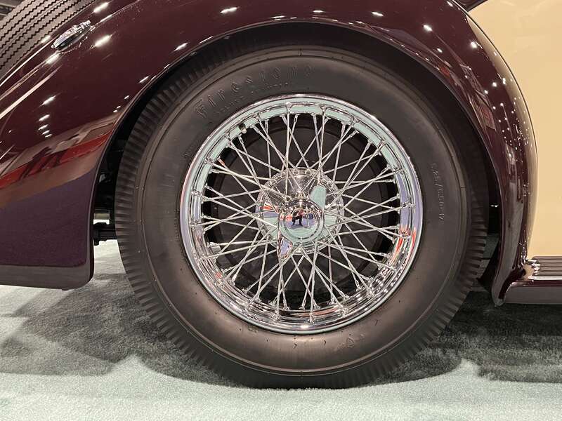 A wire spoke wheel of a vintage automobile at the 2023 Denver Auto Show.