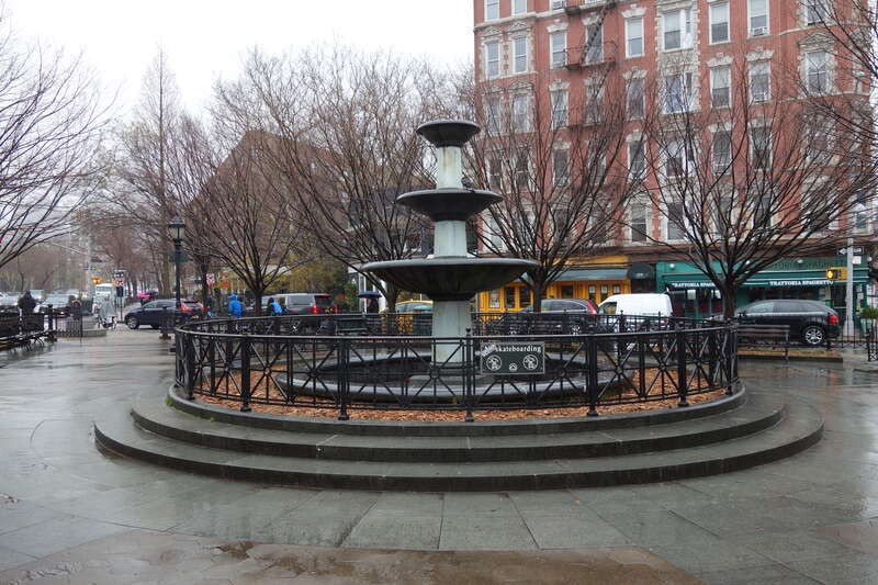 The fountain of Father Demo Square on a rainy day, at 6th Avenue, Carmine Street and Bleeker Street in Greenwich Village, Manhattan. It is currently not on, perhaps because of the rain, or because it has been snowing so much lately.