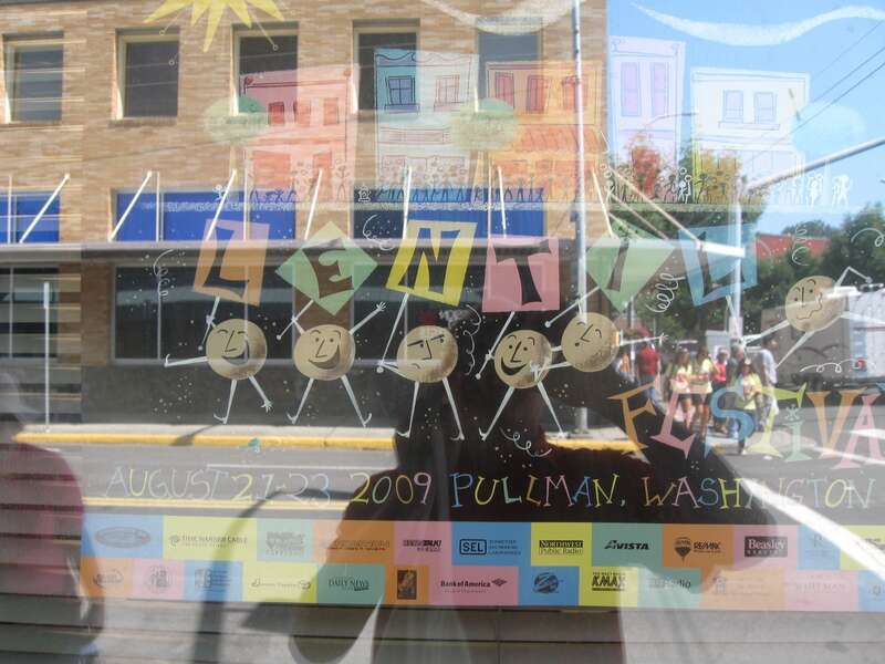 Lentil festival ad in window drowned out by reflection of Main Street