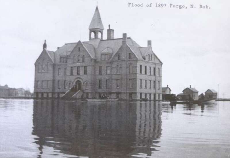 A large building surrounded by flood waters in April of 1897.  The picture was taken from somewhere in Fargo, ND.