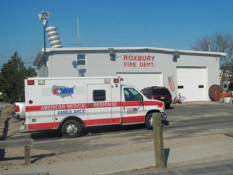 Looking north at ambulance in front of Roxbury firehouse on a sunny midday.