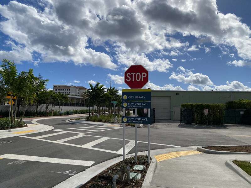 Street just down from the Boca Raton Brightline station showing directional signage leading out of it.