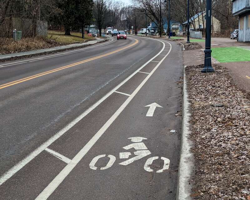 This photo shows an example of a bicycle lane with a buffered space between it and the adjacent motor vehicle lane.  There is protection or physical protection in this buffer, only painted lines.